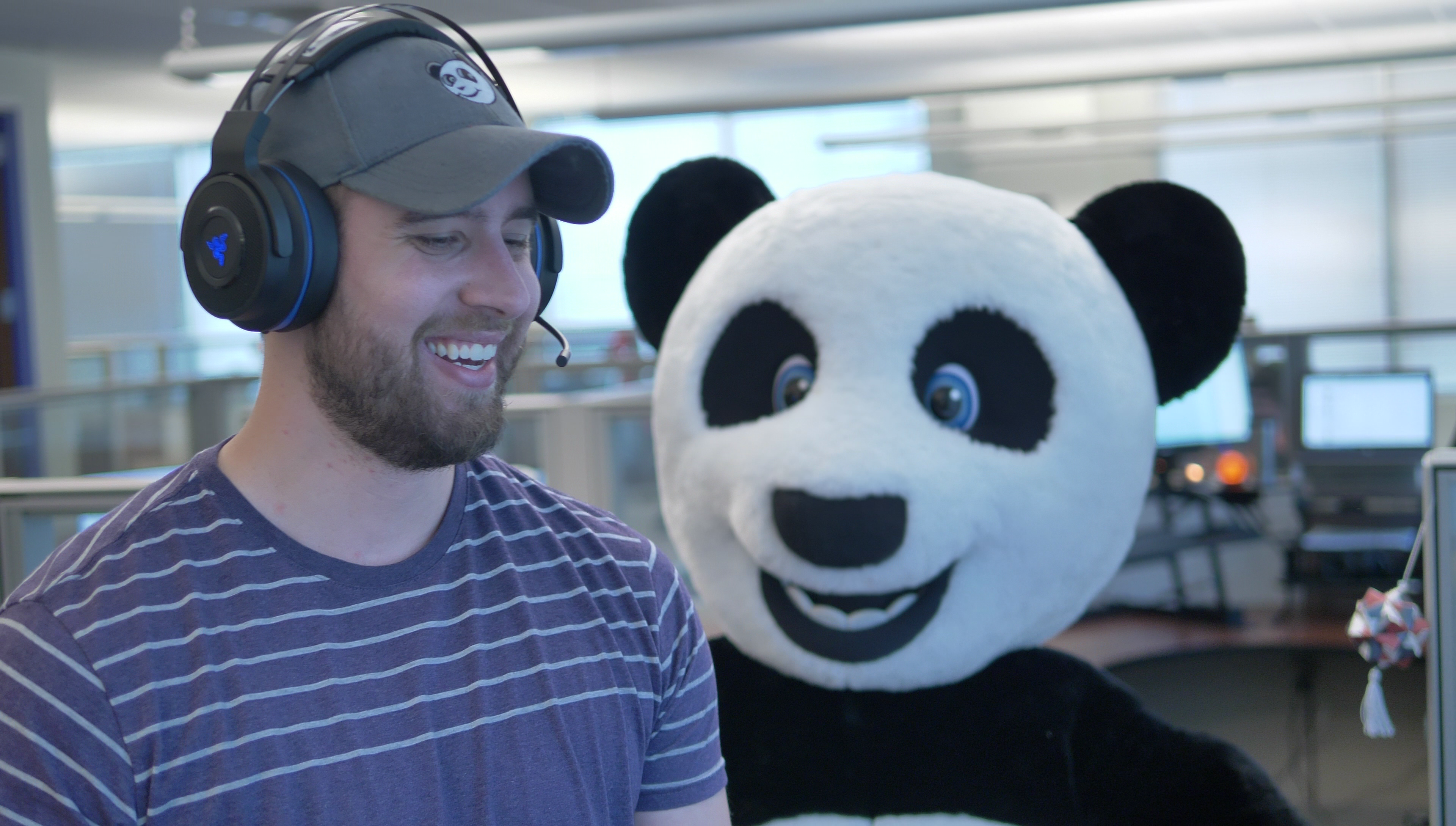 An Asset Panda employee wearing a headset is accompanied by a person in a panda costume.