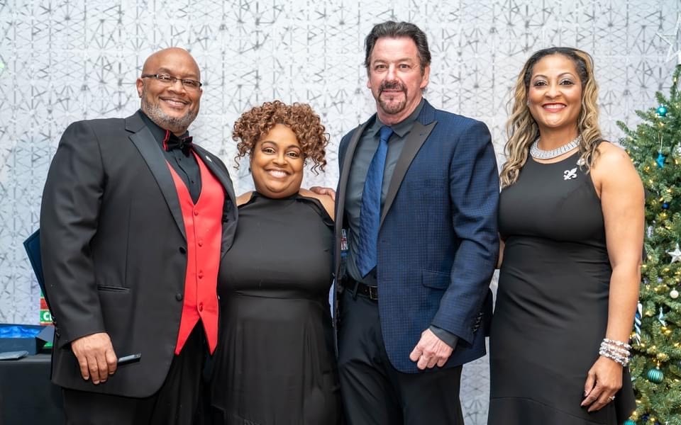 Four adults gather for a photo at an event for the Collin County Black Chamber of Commerce.