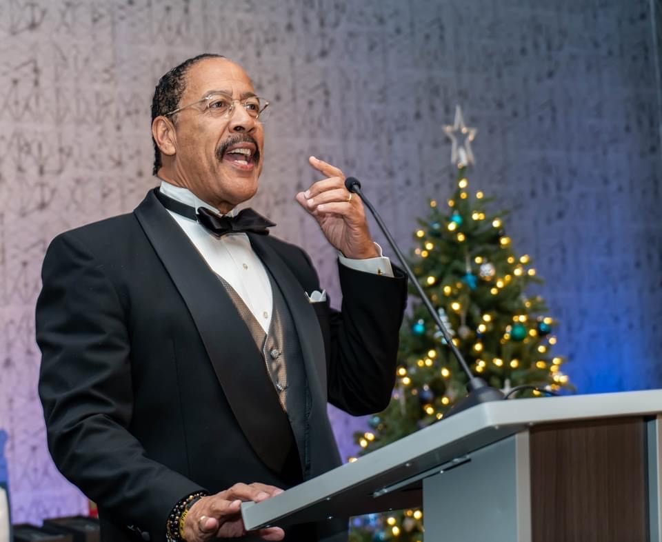 A man speaks into a microphone at the podium at an event.
