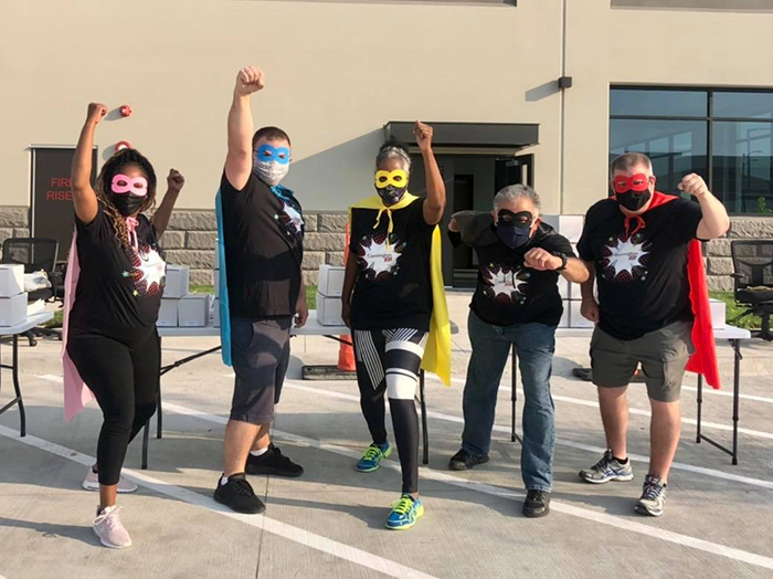 People wearing costumes with masks and capes pose for a picture.