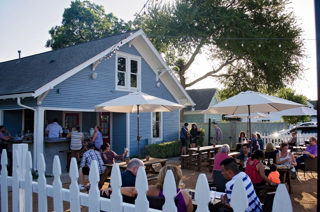 Patio with tables, a bar and live music at Eight 11 Wine Bar.