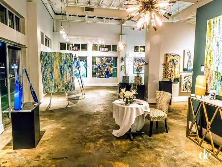 Inside an art gallery. There are paintings on the walls and on easels.