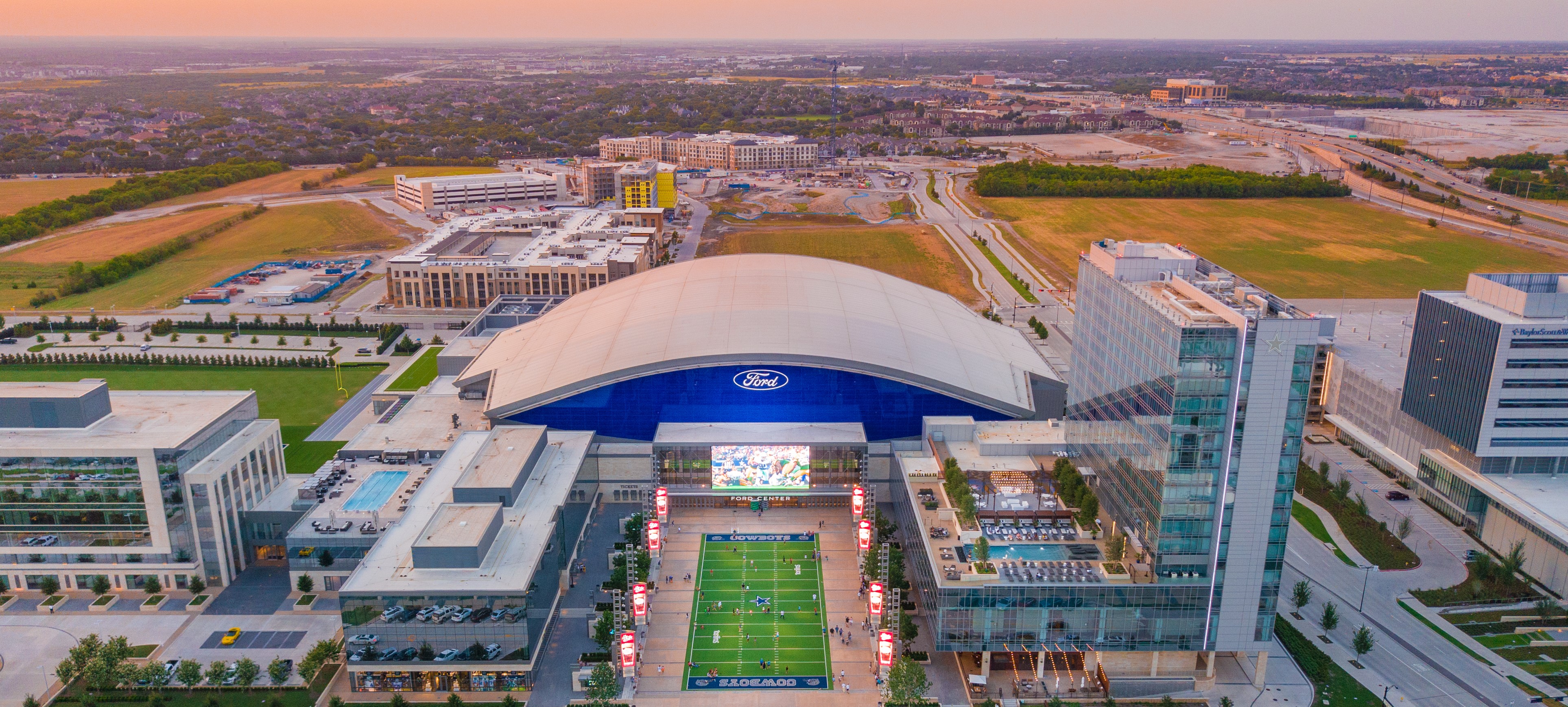 Aerial photo of Ford Center at The Star, Omni Frisco Hotel and Tostito's Plaza. There are hotels under construction in the background.